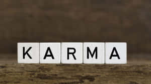 在質樸的木質表面上拼寫出 karma 的白色木塊。