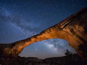 一座發光的石拱門框住了充滿銀河的鮮豔星空。