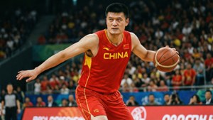 中國籃球運動員姚明在比賽中運球，背景有觀眾。