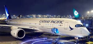 國泰航空飛機夜間停泊，帶有登機梯和跑道燈光。