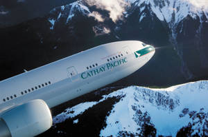 國泰航空飛機在日出時飛越白雪覆蓋的山峰。
