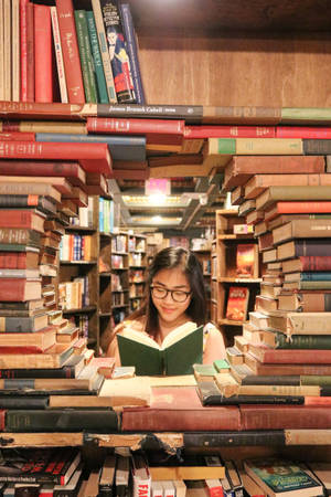 年輕女子在圖書館中被書堆環繞閱讀書籍。