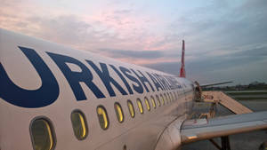 土耳其航空飛機在黃昏時分的停機坪上，機艙燈光閃爍。