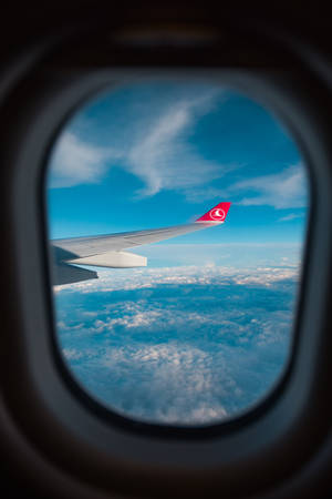 晴朗天氣下透過窗戶看到雲層上方的飛機機翼