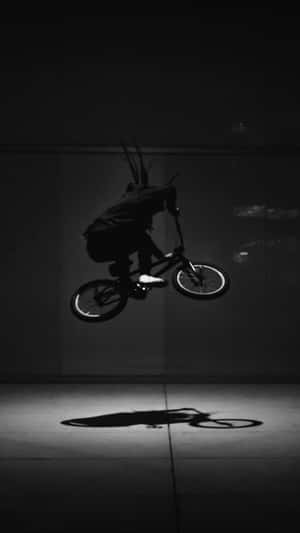 半空中形成剪影的BMX車手，在混凝土地板上投射出清晰的陰影。