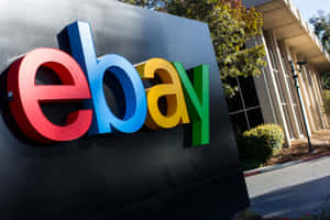 現代辦公大樓外色彩繽紛的eBay標誌招牌，有樹木和日光。