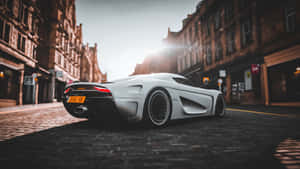 日落時白色Koenigsegg Jesko超跑停在鵝卵石街道上。