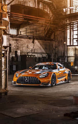 在生鏽的工業倉庫中，溫暖燈光下的橙色 Mercedes-AMG GT3 賽車。