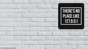 白色磚牆上的黑色標牌寫著「THERE'S NO PLACE LIKE 127.0.0.1」