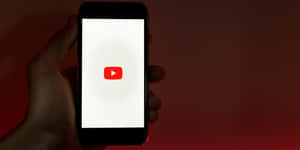 手拿著手機，屏幕上顯示YouTube應用程式圖標。 — YouTube 壁紙