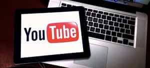 平板電腦在筆記型電腦鍵盤上顯示YouTube標誌。 — YouTube 壁紙