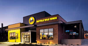 Buffalo Wild Wings 餐廳外部在黃昏時分亮起，帶有發光的黃色招牌和磚砌外牆。