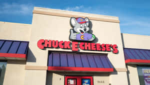 Chuck E Cheese's restaurant with mascot sign and blue sky