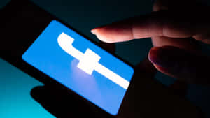 在黑暗的房間中點擊智能手機上的Facebook應用程式的手