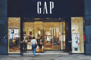 人走過一間有玻璃門和模特兒的GAP服裝店。