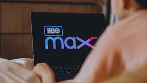 躺在床上用筆記型電腦觀看HBO Max的人。
