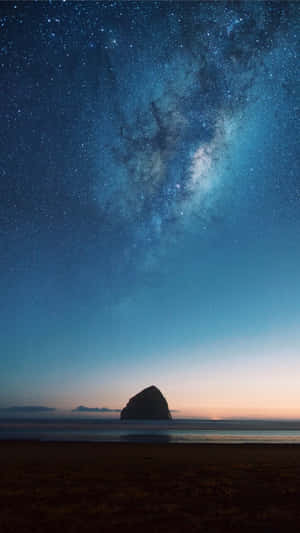在可見銀河的星空下，一座孤獨的海蝕柱。