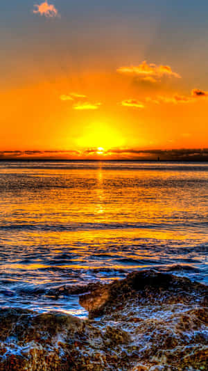 夕陽映照海洋，海浪拍打岩石