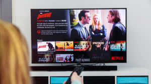 揸住遙控器嘅人睇緊Netflix電視顯示Daredevil節目頁面。