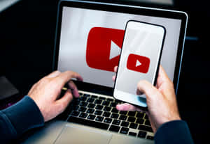使用手機和手提電腦的人，兩者都顯示YouTube標誌。 — YouTube 壁紙