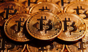 一堆金色比特幣硬幣，帶有溫暖發光的電路設計。 — 比特幣 壁紙