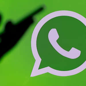 一個 WhatsApp 標誌，有一隻模糊的手指指向它。