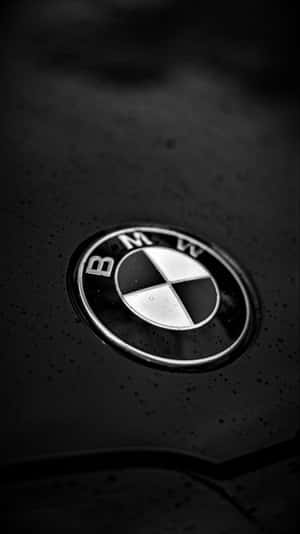 雨滴下的濕引擎蓋上的 BMW 標誌 — 9:16 壁紙