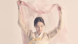穿著傳統韓服的女性手持一條粉紅色絲巾。