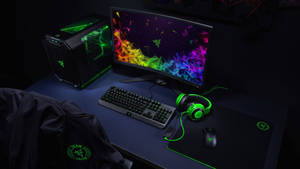 帶有發光綠色 Razer 周邊設備和彩色顯示器桌布的遊戲桌。 — 遊戲 壁紙