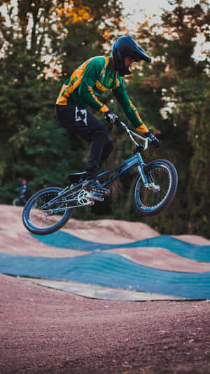 BMX車手在半空中於泥土賽道上跳躍，帶有藍色軟墊。