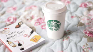 Starbucks咖啡杯同《BJ單身日記》書本喺花紋絎縫床罩上面。
