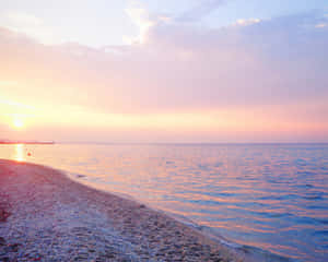 平靜海面上的夕陽，卵石海灘反射著金色的光芒