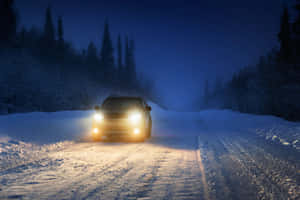 汽車在夜間行駛於積雪的森林中，車頭燈照亮道路。 — 雪 壁紙