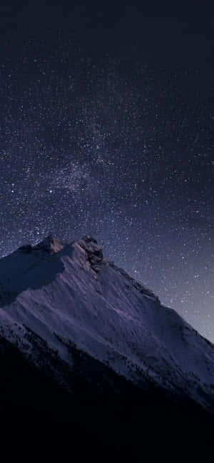 在可見銀河的星空下，積雪的山峰。 — OnePlus 壁紙