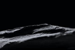 帶有戲劇性照明的深色紋理岩石表面特寫。 — 黑白 壁紙