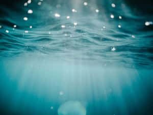 陽光透過海浪過濾的水下視圖，帶有閃爍的粒子。 — 水下 壁紙