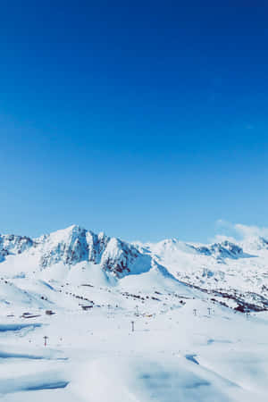 白雪覆蓋的山脈，有滑雪纜車和小型建築，在清澈的藍天下。