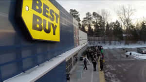 日落時分，在積雪的冬季停車場中，Best Buy商店外的人群。