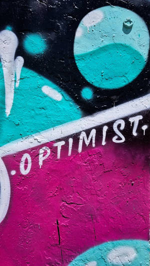 塗鴉壁畫，以青綠色和洋紅色在粗糙牆壁上拼寫「optimist」。 — 塗鴉 壁紙