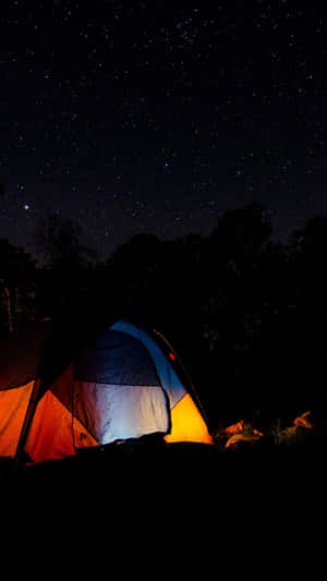 在繁星點點的夜空下，被樹木環繞的明亮帳篷。 — 夜空 壁紙