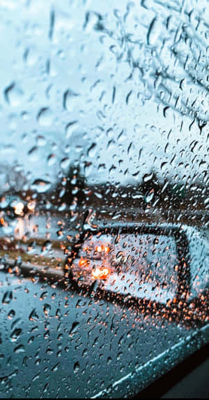 汽車車窗上的雨滴，背景中模糊的城市燈光閃爍。