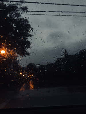 黑暗夜晚中，車窗上的雨滴與發光的街燈。