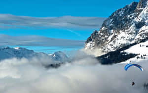 滑翔傘飛越積雪的山峰和雲層。
