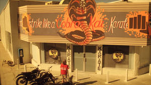 Cobra Kai 空手道道場，有眼鏡蛇壁畫和停在外面的摩托車。