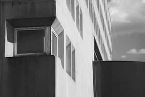 現代主義建築外牆，具有幾何窗戶和強烈陰影，在陰天天空下。 — 建築 壁紙