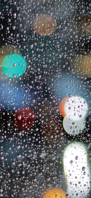 玻璃上的雨滴，背後是模糊多彩的城市燈光。