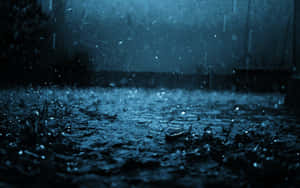 在深藍色夜空下，雨點濺落在潮濕的路面上。
