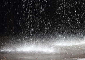 夜間雨滴落在潮濕表面並濺起水花。