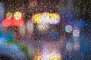 玻璃上的雨滴，背景是夜晚模糊的城市燈光