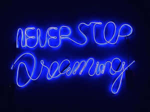 藍色霓虹燈牌，上面有「Never Stop Dreaming」字樣，在夜間發光。 — 霓虹藍色美學 壁紙
